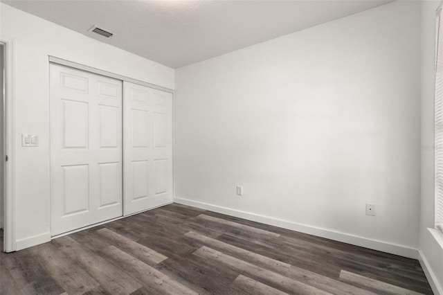 unfurnished bedroom with dark hardwood / wood-style floors and a closet