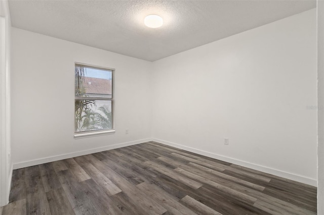 empty room featuring dark wood-type flooring and a textured ceiling