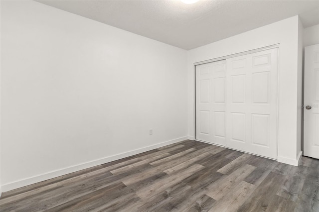 unfurnished bedroom featuring dark hardwood / wood-style flooring and a closet