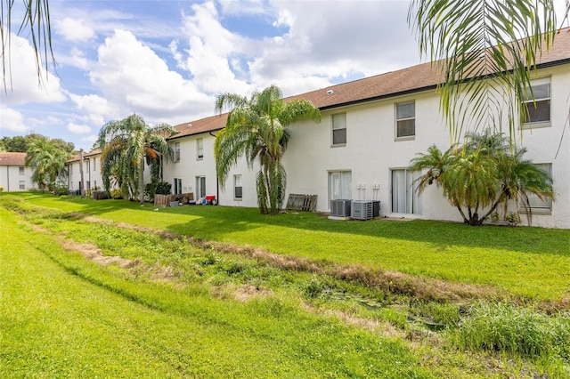 back of house featuring central AC unit and a lawn