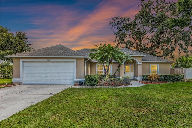 ranch-style house featuring a garage and a yard