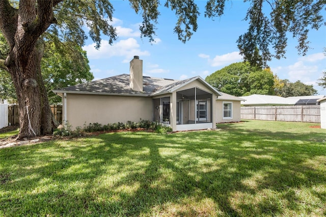 back of property with a sunroom, a yard, and ceiling fan