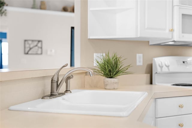 details featuring white range, white cabinetry, and sink