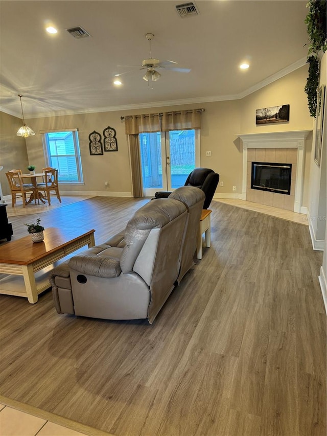 living room with crown molding, a fireplace, ceiling fan, and hardwood / wood-style flooring