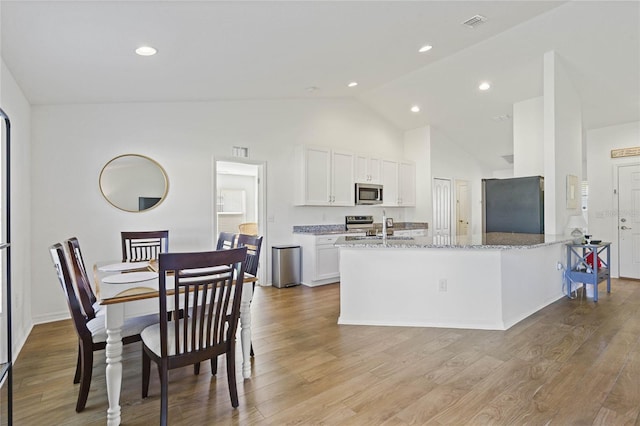 kitchen featuring light stone countertops, stainless steel appliances, light hardwood / wood-style floors, and white cabinetry