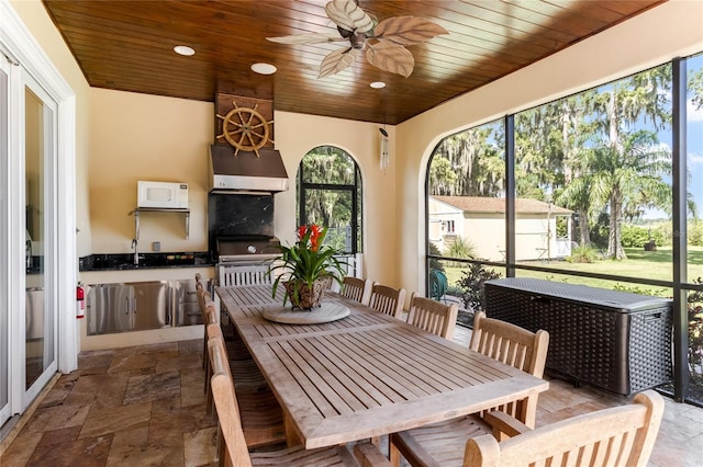 sunroom featuring wood ceiling and ceiling fan