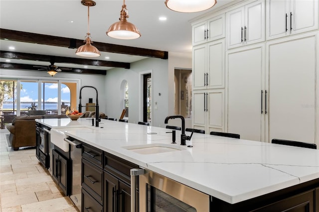 kitchen featuring light stone countertops, a large island, beverage cooler, decorative light fixtures, and sink