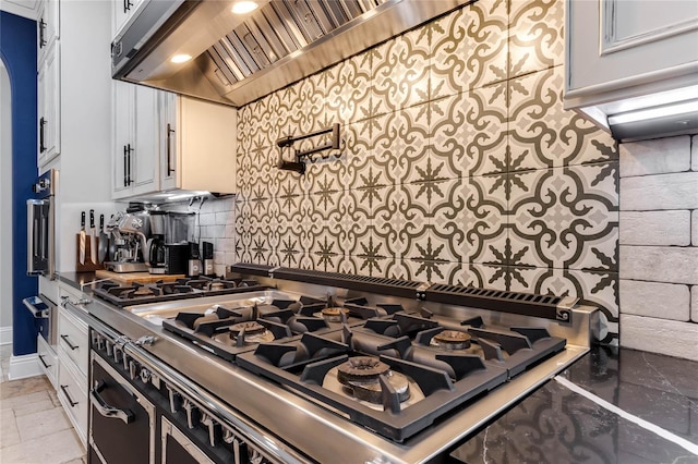 kitchen featuring stainless steel gas stovetop, wall chimney exhaust hood, and white cabinets