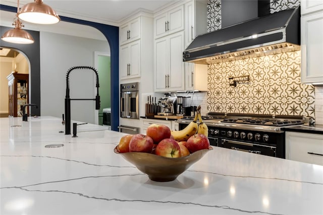 kitchen with dark stone counters, white cabinets, custom exhaust hood, decorative backsplash, and stainless steel appliances