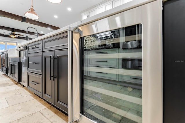 interior space featuring beam ceiling, ceiling fan, and white cabinetry