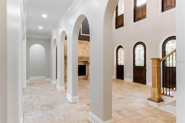 entryway with ornamental molding and a towering ceiling