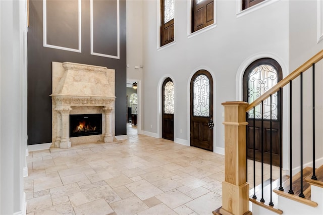 foyer entrance with a high ceiling, a fireplace, and a healthy amount of sunlight