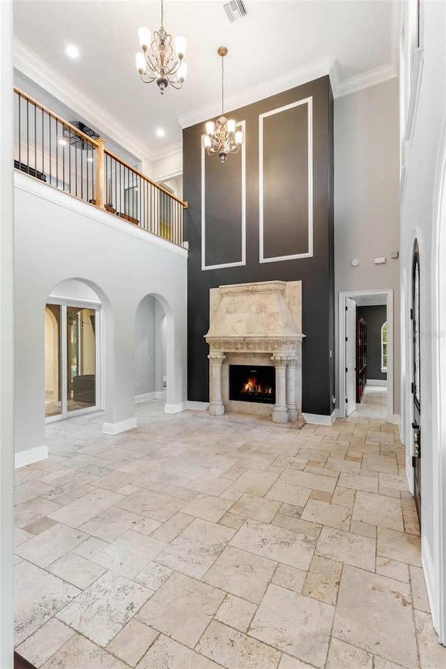 unfurnished living room with ornamental molding, a towering ceiling, a chandelier, and a fireplace