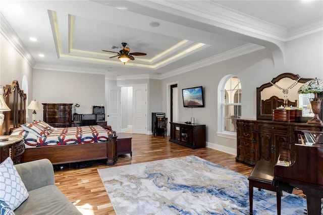 bedroom with ornamental molding, ceiling fan, a raised ceiling, and hardwood / wood-style flooring