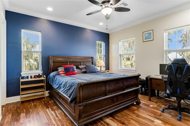 bedroom featuring ceiling fan, multiple windows, hardwood / wood-style floors, and crown molding