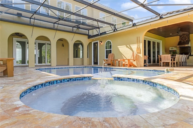 view of pool with glass enclosure, an in ground hot tub, ceiling fan, french doors, and a patio area