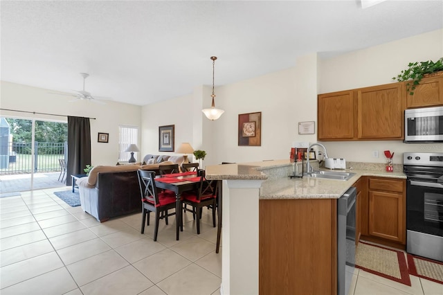 kitchen with light tile patterned flooring, sink, kitchen peninsula, hanging light fixtures, and appliances with stainless steel finishes