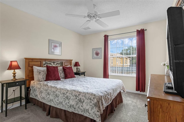 bedroom featuring a textured ceiling, ceiling fan, and light colored carpet