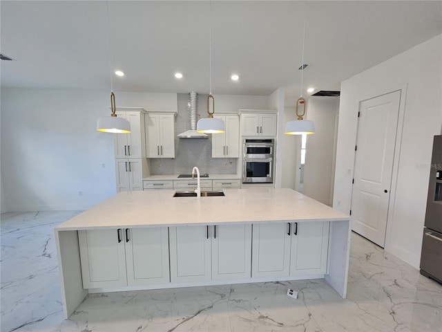 kitchen featuring wall chimney range hood, pendant lighting, a large island, and double oven