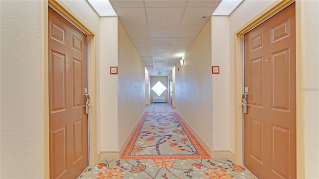 hall featuring a paneled ceiling and tile patterned floors