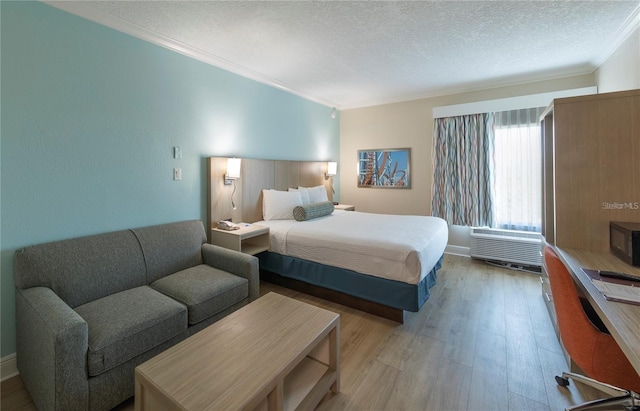 bedroom with ornamental molding, a textured ceiling, and light hardwood / wood-style floors