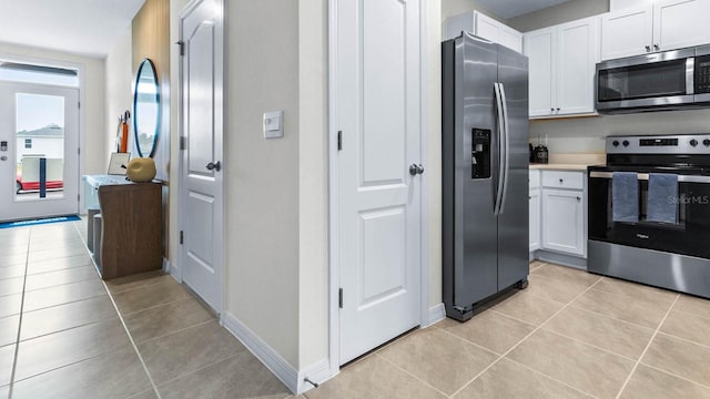 kitchen with stainless steel appliances, white cabinets, and light tile patterned floors