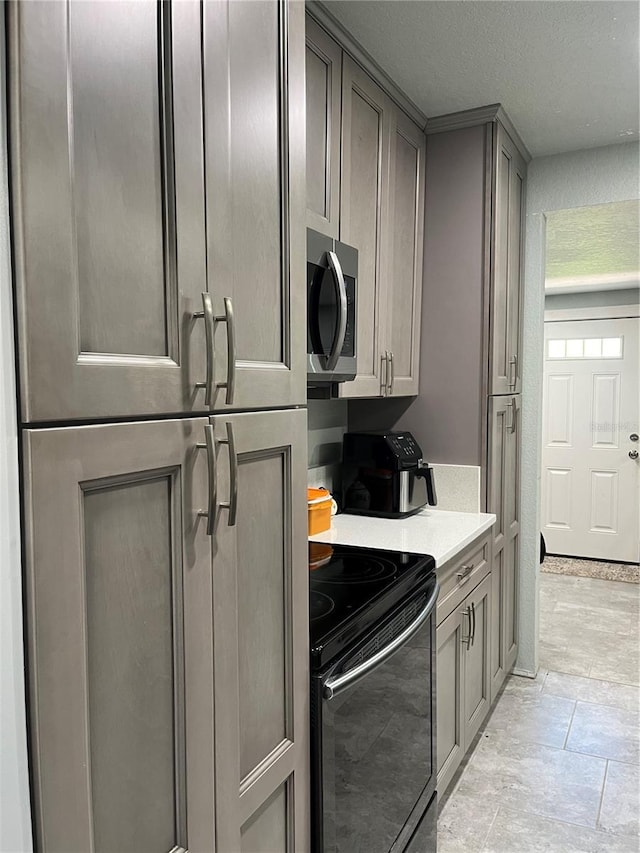 kitchen featuring black / electric stove, gray cabinets, and paneled built in refrigerator