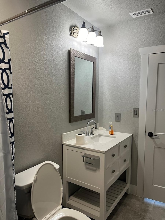 bathroom featuring vanity, toilet, and a textured ceiling