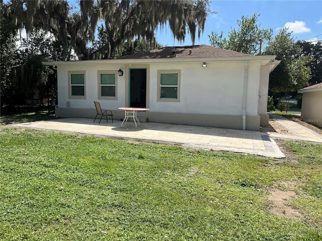 rear view of property featuring a patio and a lawn