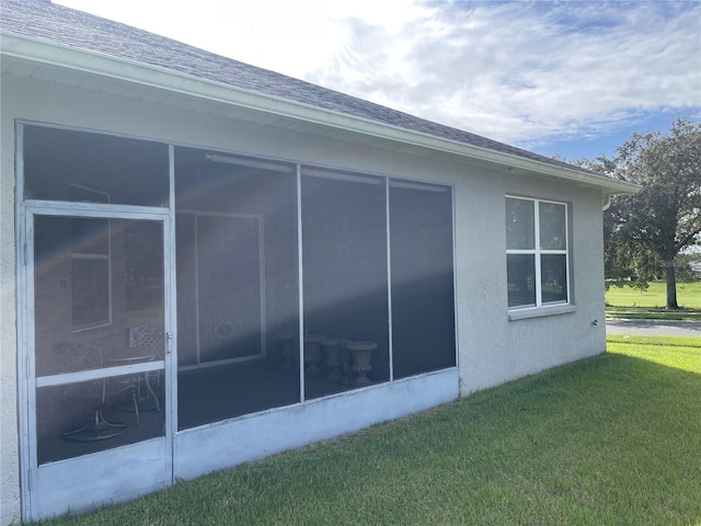 view of property exterior with a sunroom and a lawn