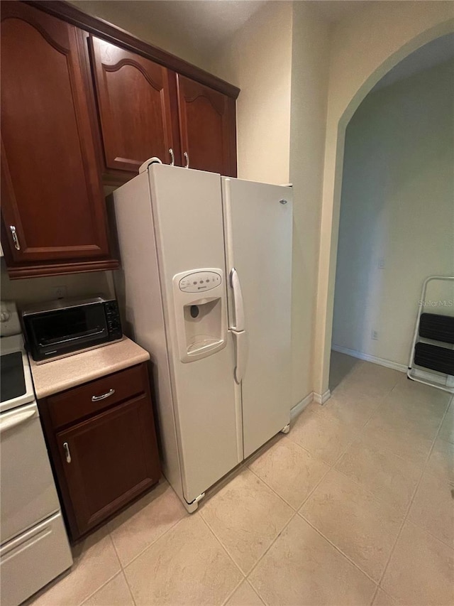 kitchen with heating unit, electric range oven, light tile patterned floors, and white refrigerator with ice dispenser