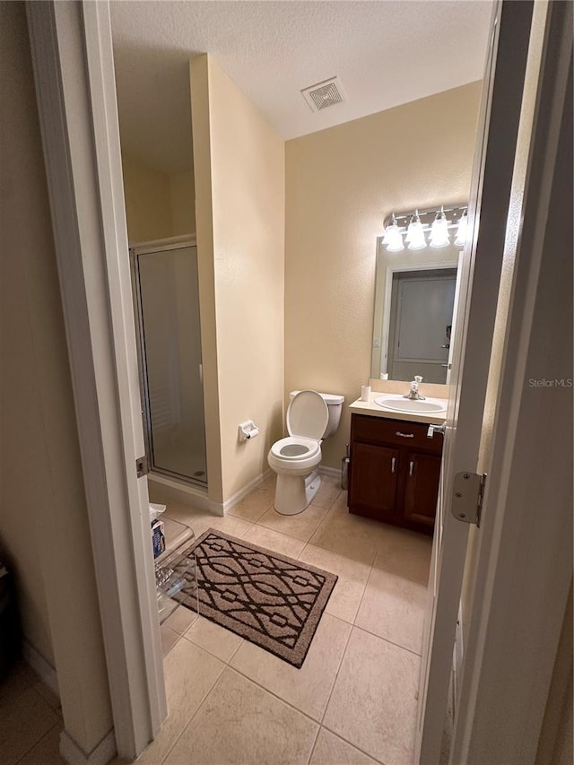 bathroom with toilet, an enclosed shower, a textured ceiling, vanity, and tile patterned flooring