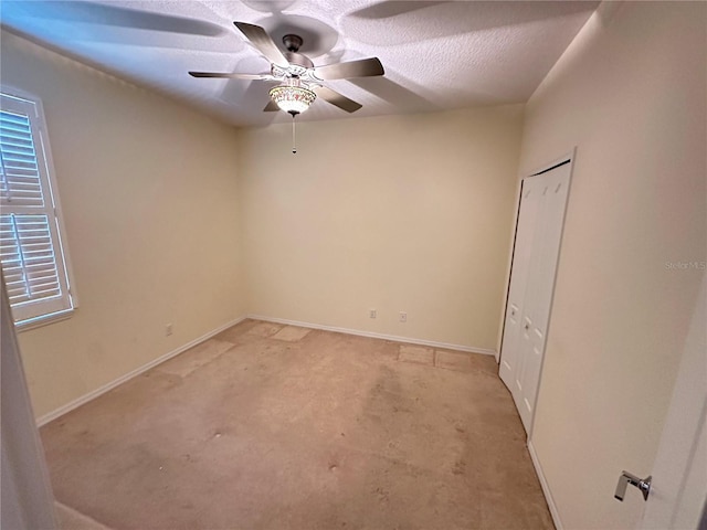 carpeted spare room with ceiling fan and a textured ceiling