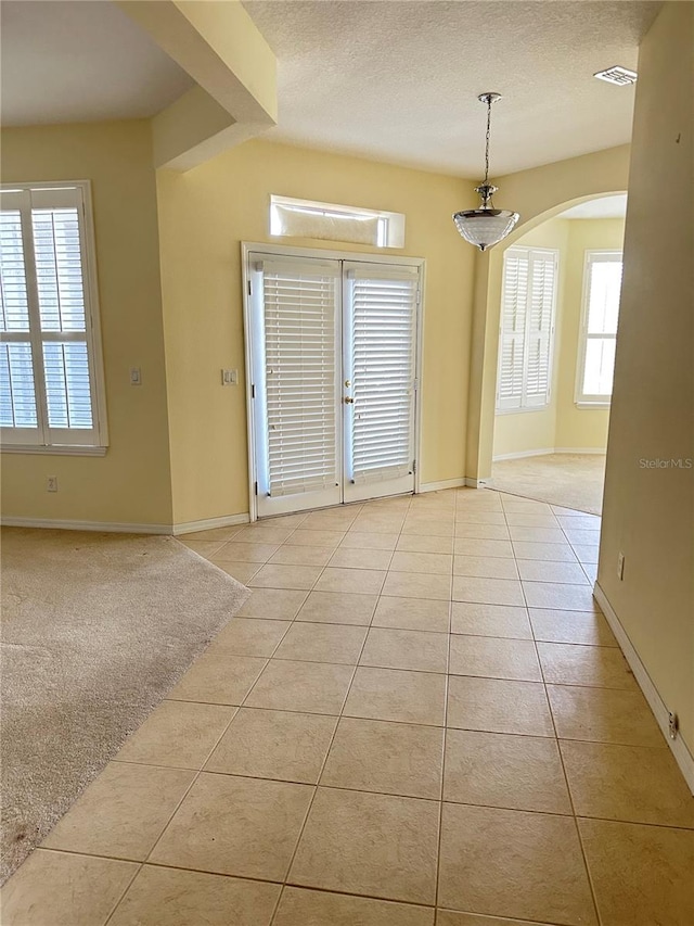 empty room featuring a textured ceiling and light tile patterned floors