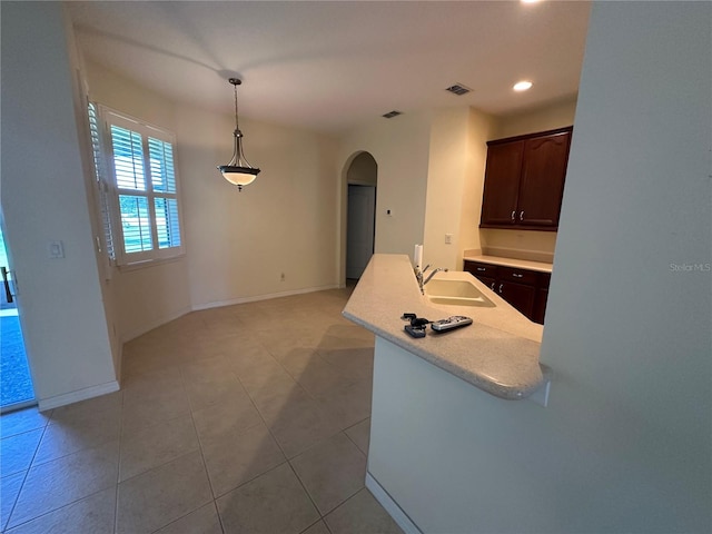 kitchen with dark brown cabinetry, sink, light tile patterned floors, and hanging light fixtures