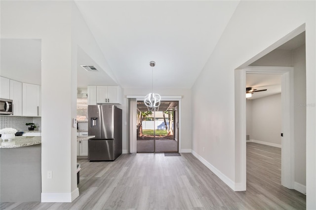 kitchen featuring stainless steel appliances, light wood-type flooring, tasteful backsplash, and white cabinetry