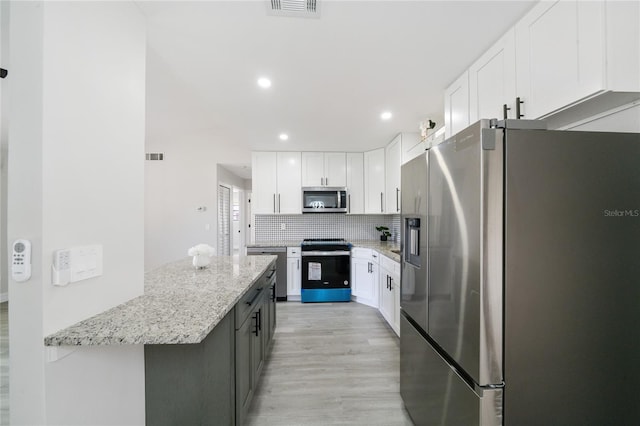 kitchen featuring light stone counters, tasteful backsplash, white cabinetry, stainless steel appliances, and light hardwood / wood-style floors