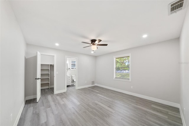 unfurnished bedroom with light hardwood / wood-style flooring, a closet, ceiling fan, and a walk in closet