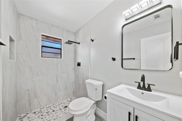 bathroom featuring a tile shower, vanity, and toilet