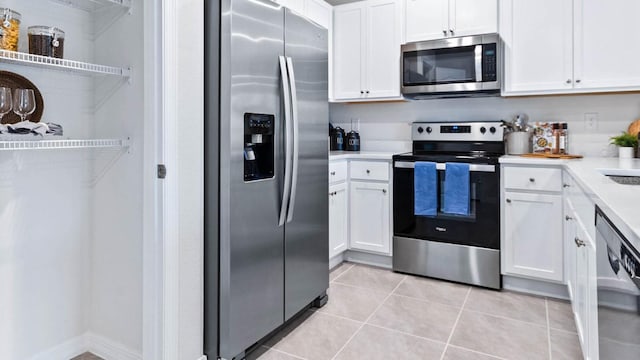 kitchen with light tile patterned floors, stainless steel appliances, and white cabinets