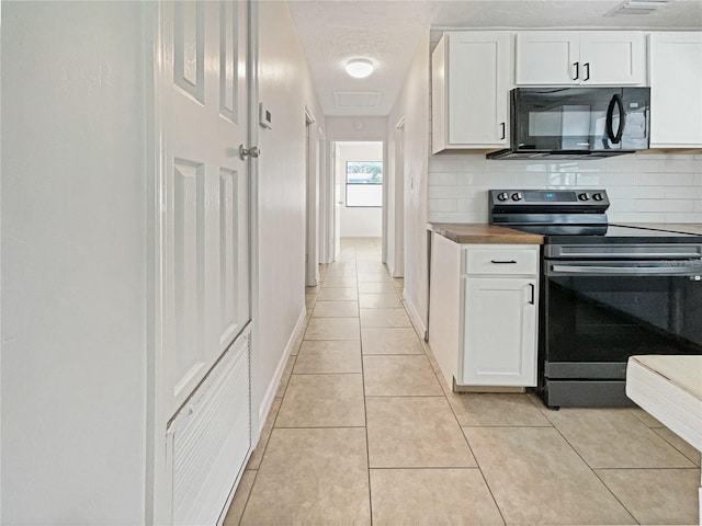 kitchen with black appliances, white cabinetry, light tile patterned floors, and tasteful backsplash