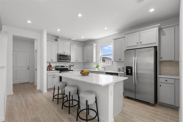 kitchen featuring sink, stainless steel appliances, a kitchen breakfast bar, a center island, and light wood-type flooring