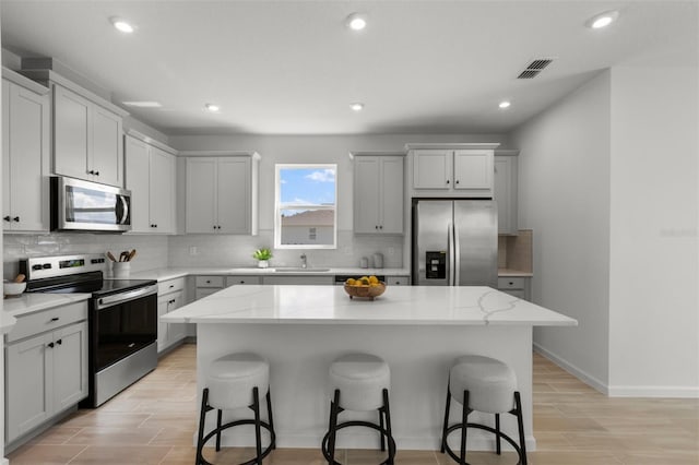 kitchen featuring sink, appliances with stainless steel finishes, a kitchen bar, and a kitchen island