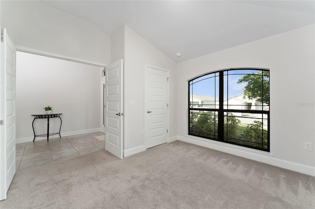 unfurnished bedroom with light carpet, lofted ceiling, and a closet