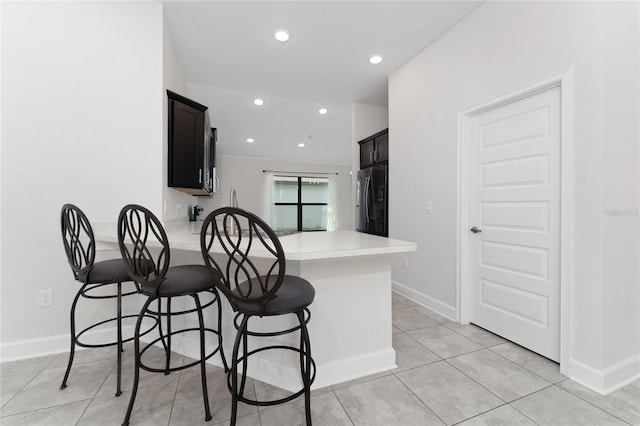 220 Bergamot Loop, Davenport, FL 33837 - kitchen featuring stainless steel fridge, light countertops, a peninsula, a kitchen bar, and recessed lighting