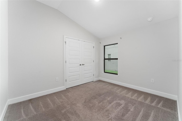 carpeted empty room with vaulted ceiling