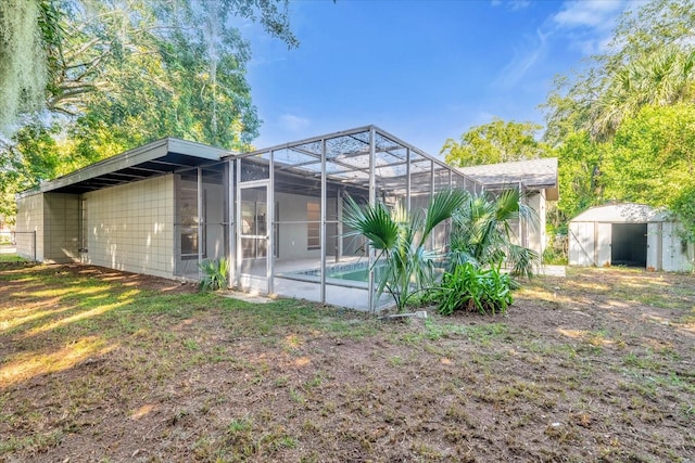 rear view of property with a lanai, a patio, and a storage unit