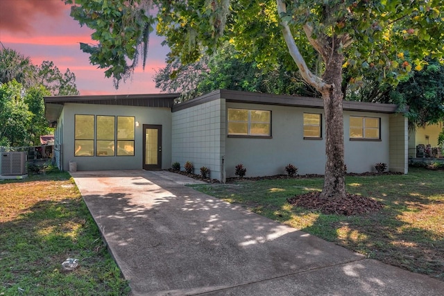 view of front of house with cooling unit and a lawn