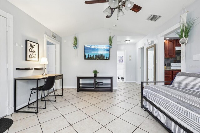 bedroom with light tile patterned floors, vaulted ceiling, ceiling fan, and ensuite bathroom