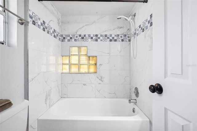 bathroom with tiled shower / bath combo and toilet